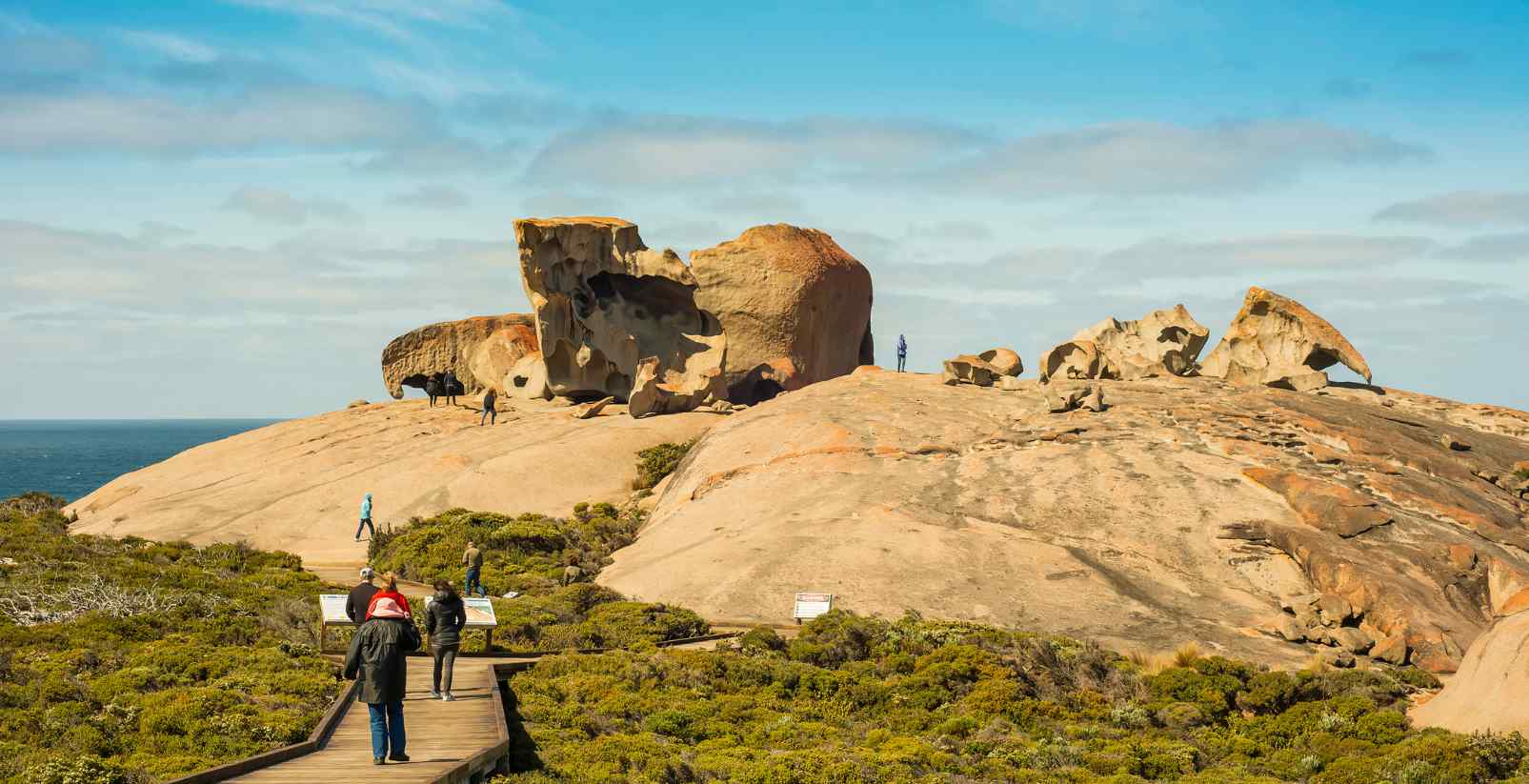 People walking around Rock formation near beach on Kangaroo Island